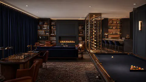 The club lounge with a fireplace and a wine cabinet
